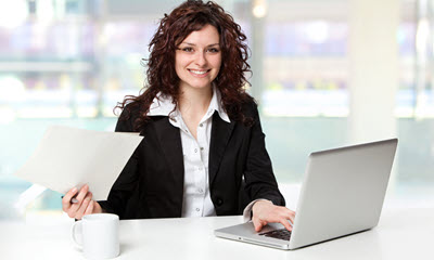 Image of woman on a computer and holding paper